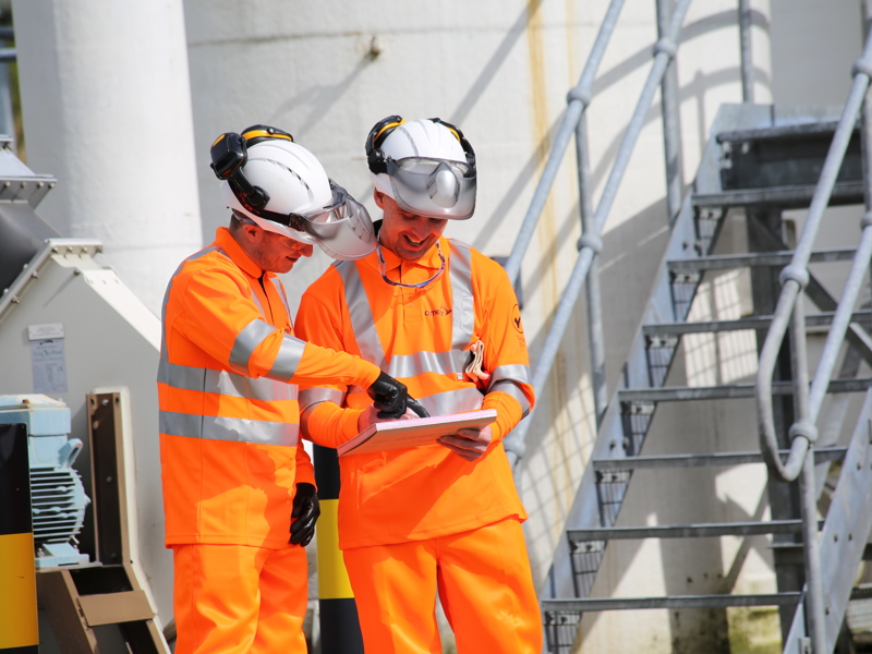 Two Amey employees in PPE, inspecting a document,