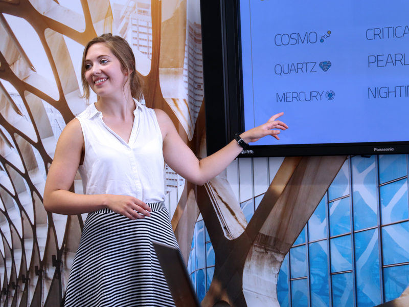 Image of a woman, presenting pointing at a screen.