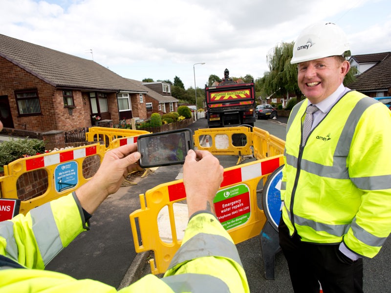 two Amey employees in PPE stood in front of roadworks. 