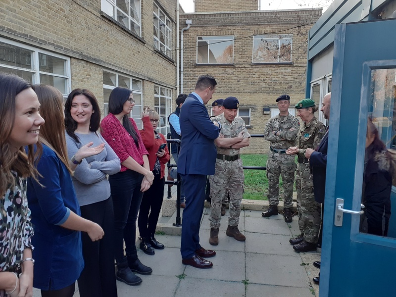 a group of military and Amey personnel stood in a courtyard chatting. 