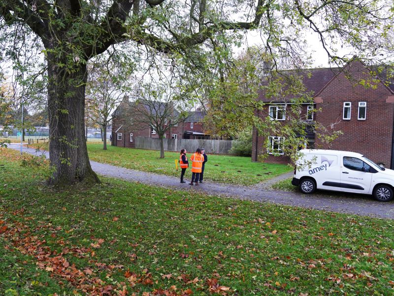 Three Amey, male employees in PPE in front of a building