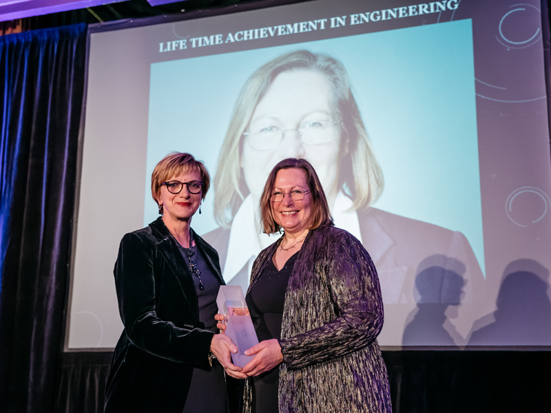 Two women, holding an award.