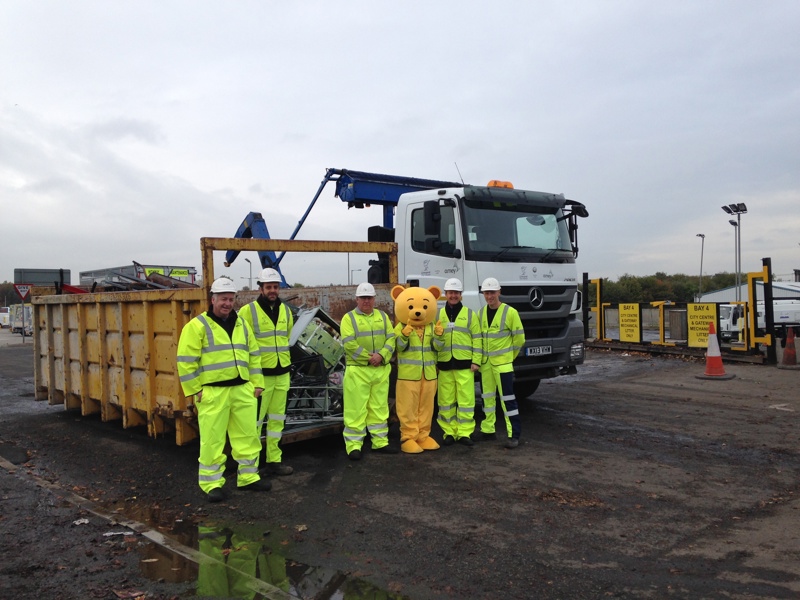 A group of Amey workers stood in front of a skip.