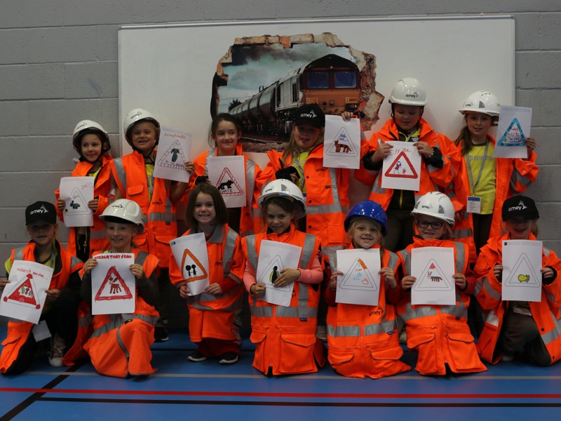 Girl guides in PPE, holding poster they have made.