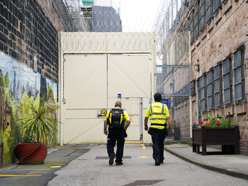 Image of Amey employees walking towards prison gates
