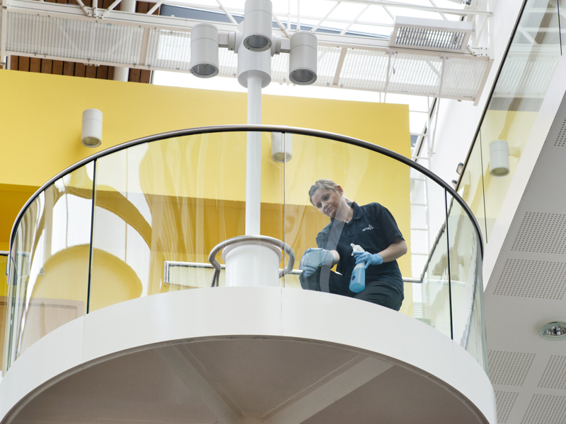 Image of a woman, cleaning a circular glass wall.