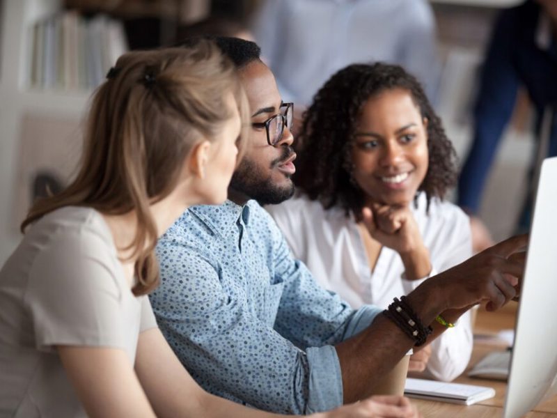 Image of two women and a man sharing a computer screen.