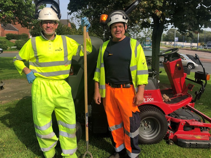 Image of two Amey employees in PPE holding gardening tools.
