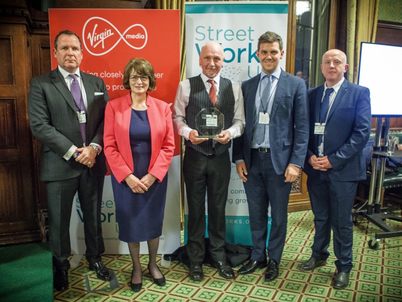 A group of Amey employees, in formal attire, holding an award.