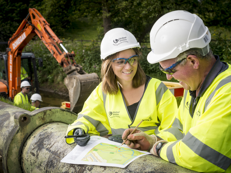 two people in PPE, inspecting a map.