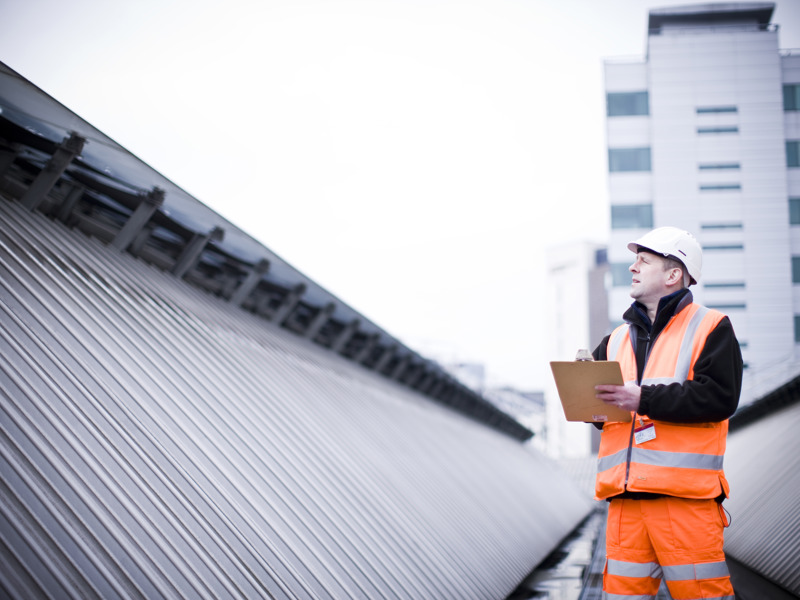 a man in PPE inspecting a roof.