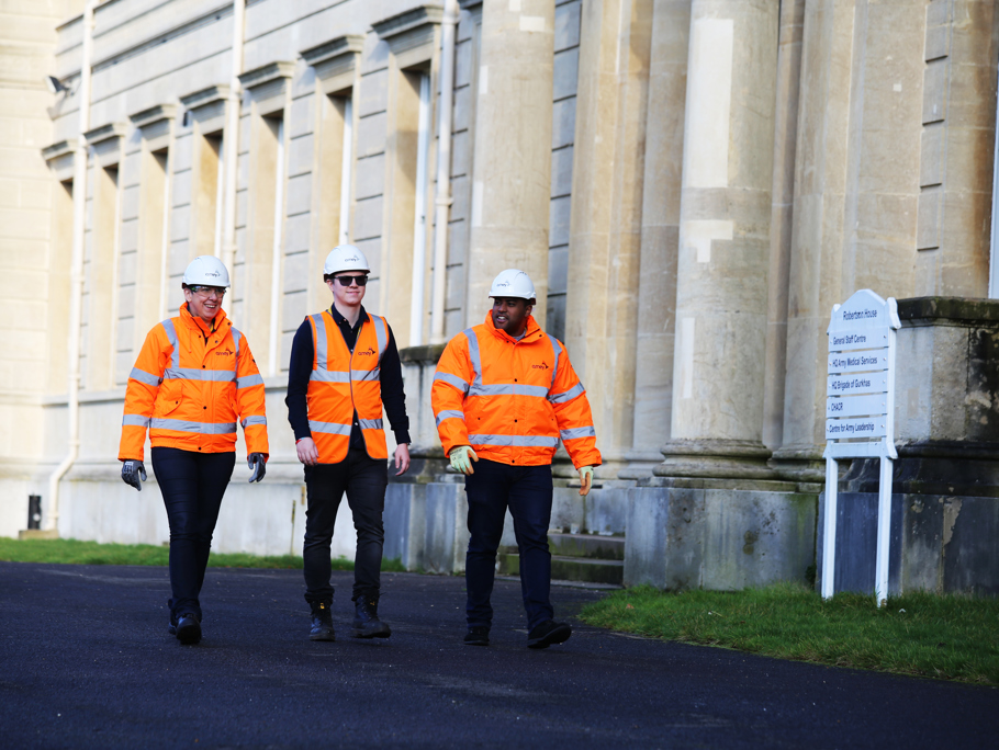 Image of three Amey employees walking in front on a building.