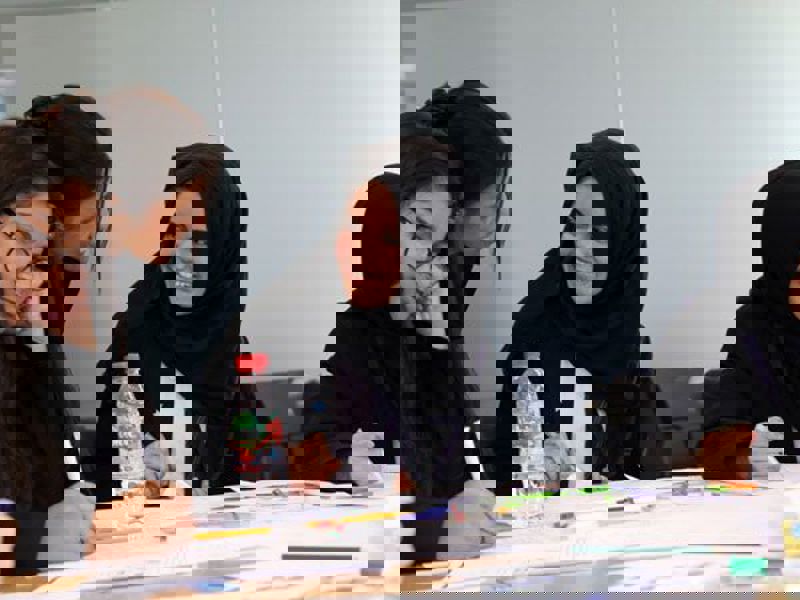 Image of women wearing hijabs working at a desk.