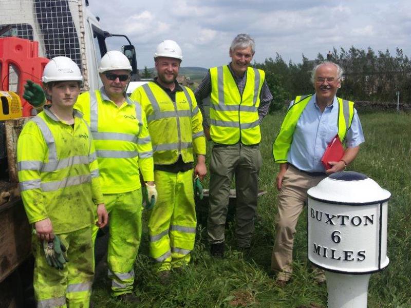 Image of Amey employees in PPE stood in front of a 'six miles to Buxton' post.
