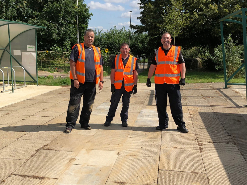 Three Amey male employees wearing hi vis, stood on a patio.