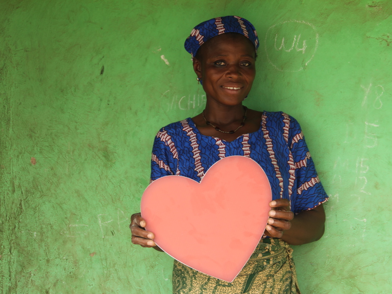 A lady holding a cut out of a heart shape.