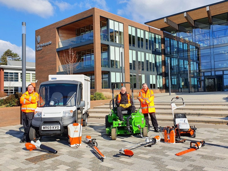Amey employees with grounds maintenance equipment, stood in front of a building.