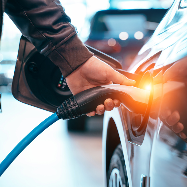 Image of a man charging an electric vehicle. 