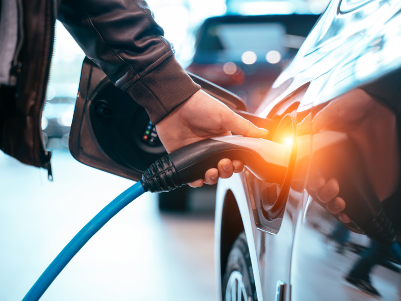 Image of a man charging an electric vehicle. 