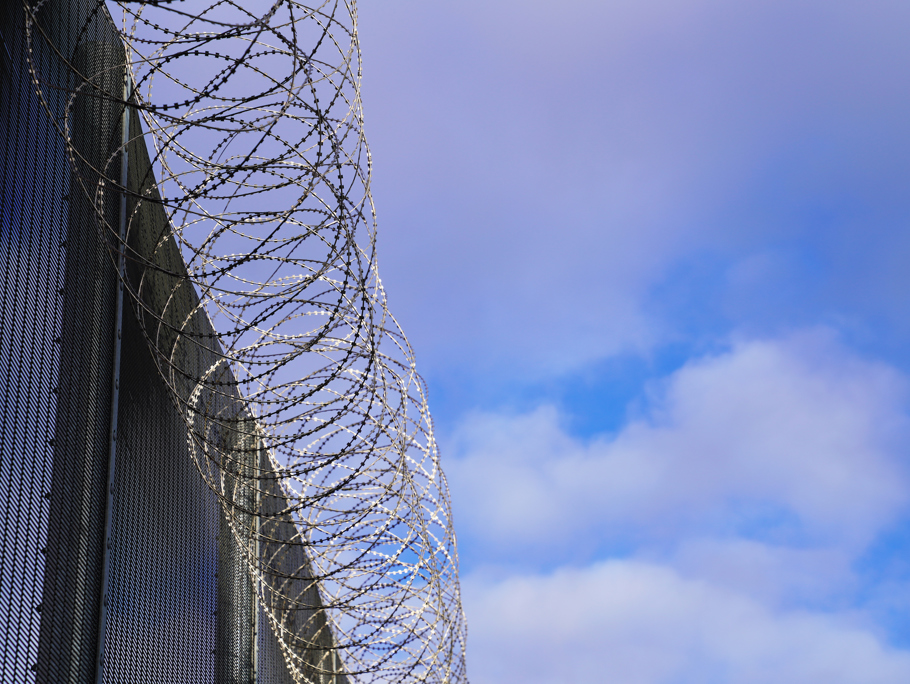 Image of  a barbed wire topped fence.