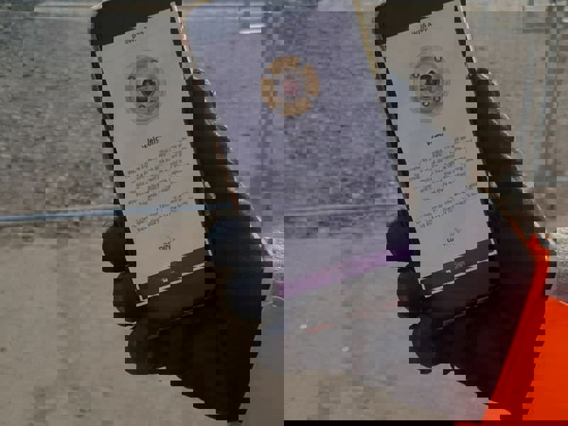 Image of a man holding a mobile, presenting a power app.