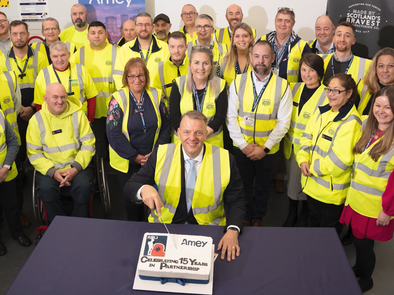 Image of Amey employees, cutting a cake, celebrating 15 years partnership with RBLI