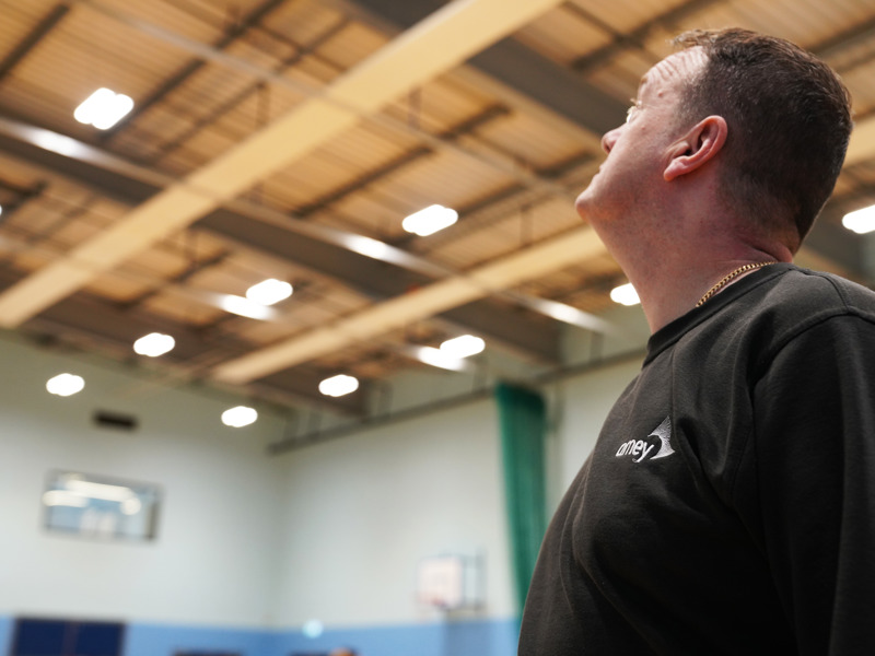 A male Amey employee looking up at a warehouse ceiling.