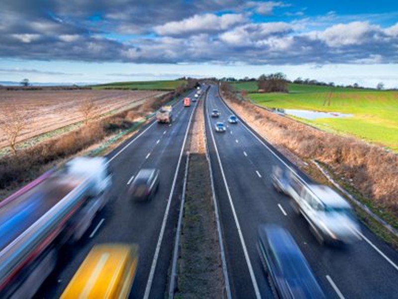 Image of a highway with cars traveling at speed, slightly blurred.