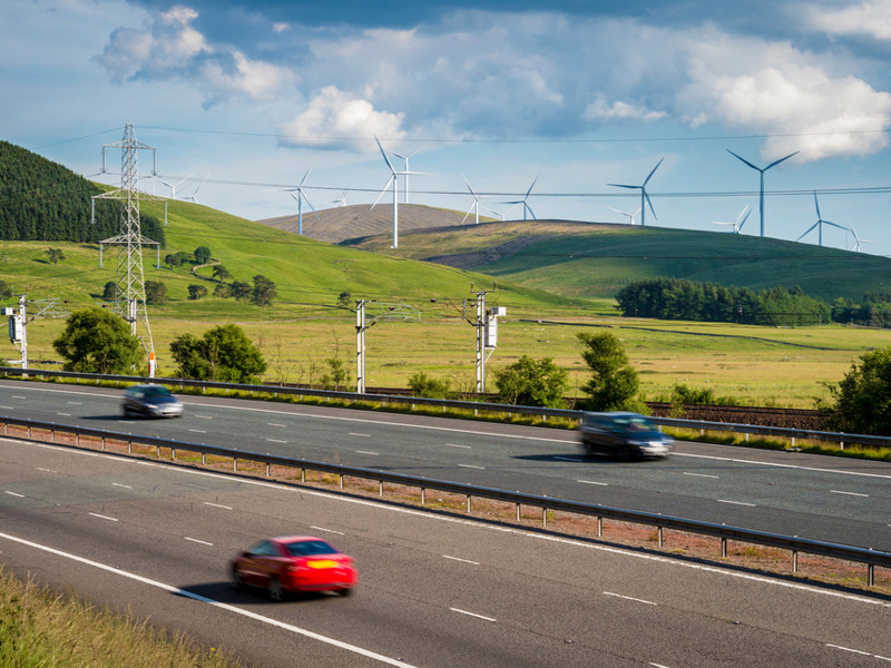 a road with cars and wind turn binds in the background.
