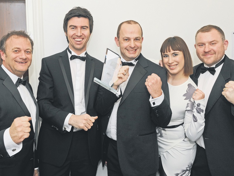 A group of Amey employees, in formal attire, holding an award.