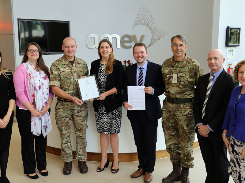 A group of Amey employees, holding three pictures in frames.