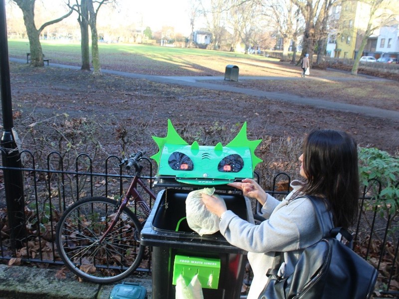 Lady putting rubbish in a bin.