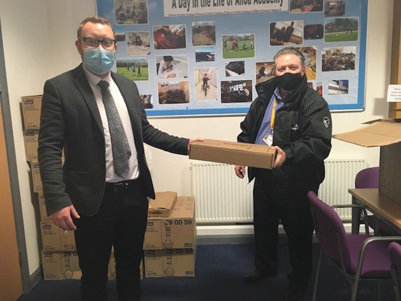 Image of two people holding a laptop that are being donated to Scottish schools.