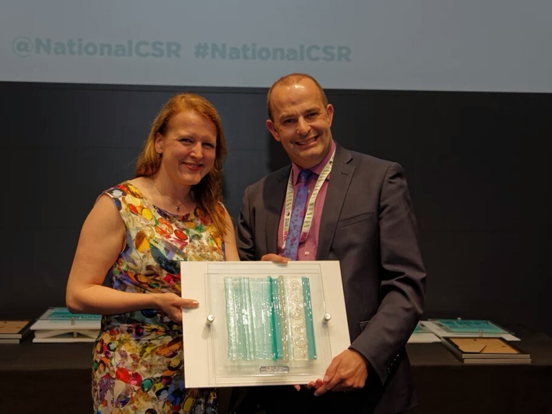 A man and a woman, holding an award.