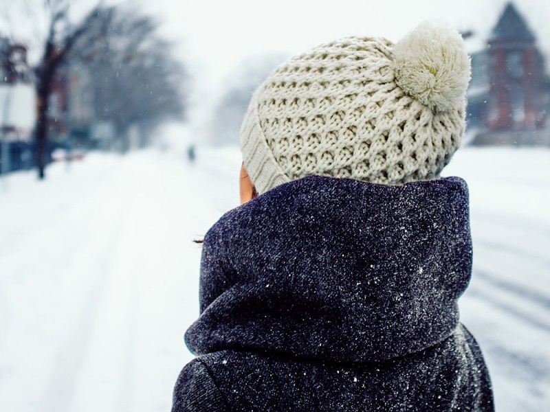 Head ad shoulder image of the back of a person wearing winter wear in the snow.