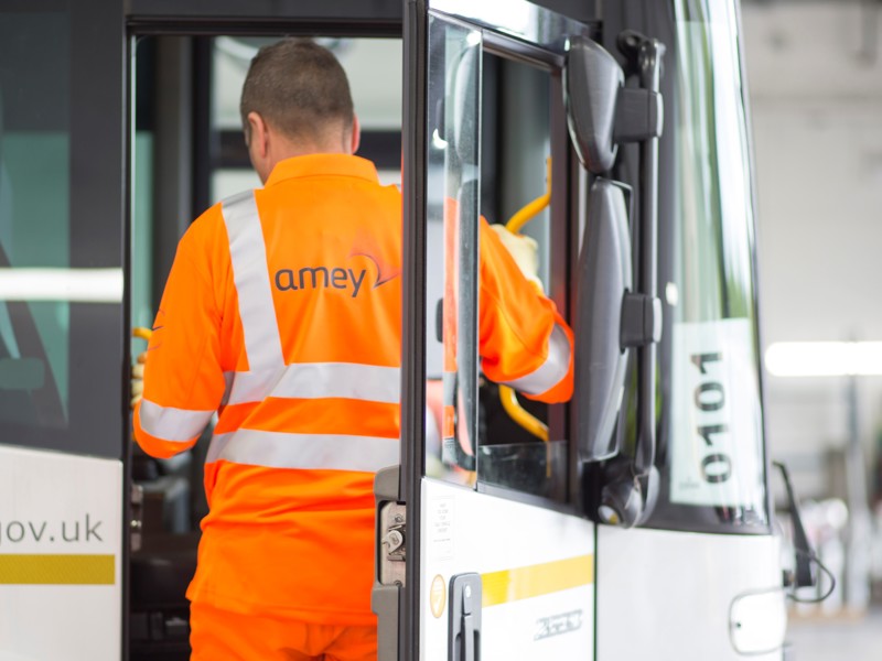 Image of an Amey employee in PPE entering a bus.