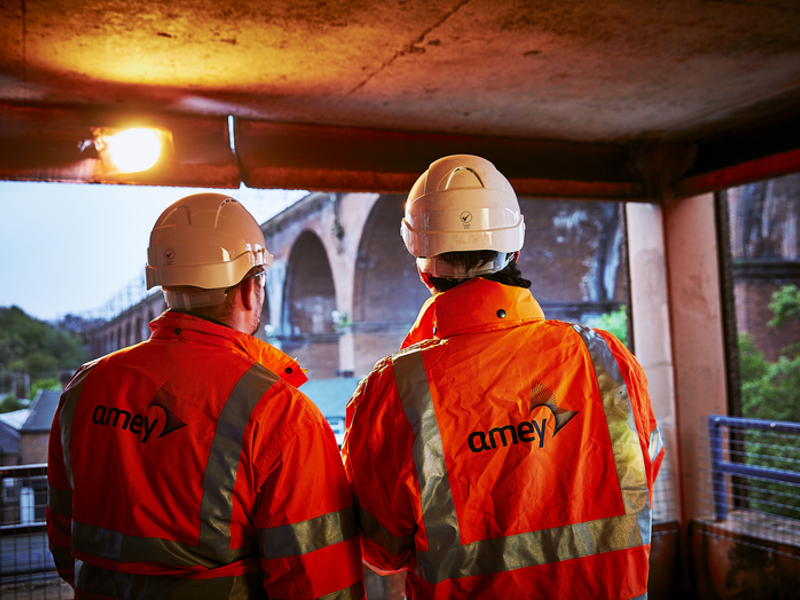 Two Amey employees wearing PPE with their backs to us.