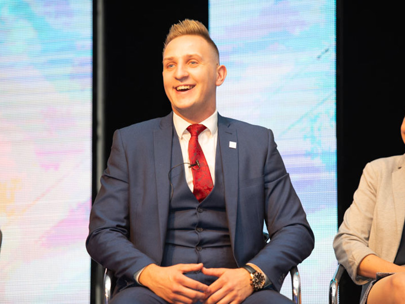 Image of a man smiling sat in a chair.