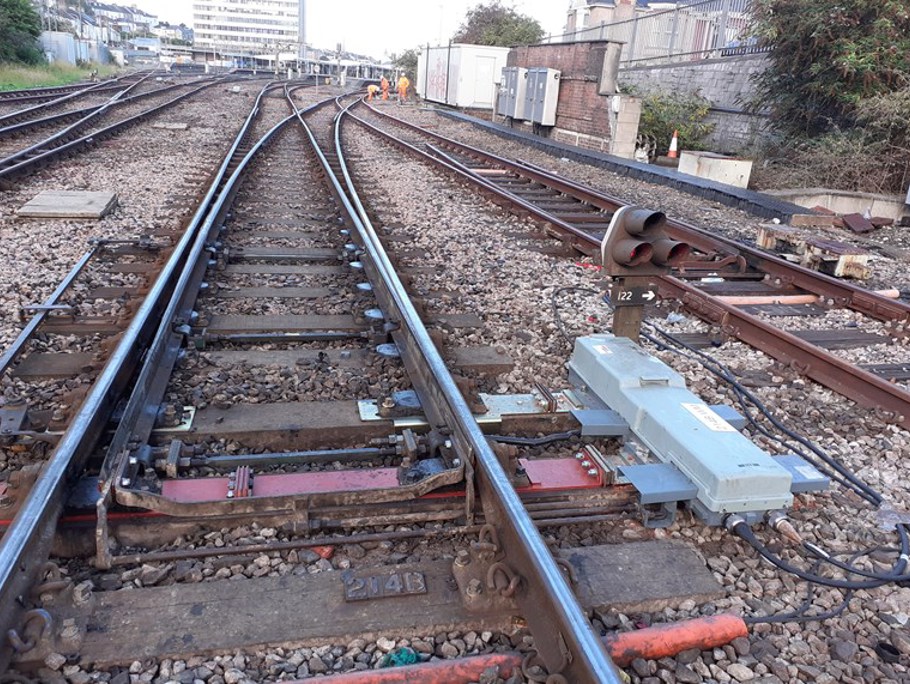 Low view of rail tracks with Amey employees in the distance 